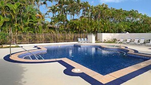 A swimming pool with a unique shape, surrounded by lounge chairs and a fence. -  A/C, Deluxe, Top Floor, Quiet Development, heated pool, convenient location (Princeville)