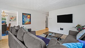 Ein modernes Wohnzimmer mit einem grauen Sofa, einem Couchtisch und einem an der Wand befestigten Flachbildfernseher.