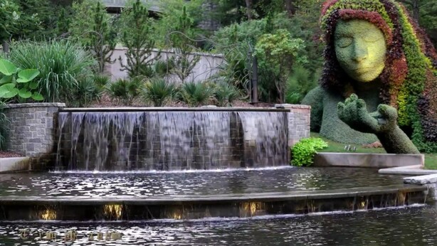 Un jardín con una cascada y una estatua.