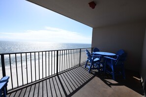 Enjoy the ocean view from this balcony with a table and chairs.