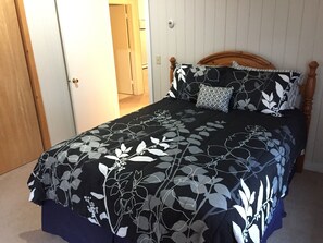 Une chambre à coucher avec un lit, une tête de lit en bois et une porte donnant sur une autre pièce.