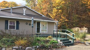 A single-story house with a front porch, a chimney, and a small staircase leading to the front door. - Cozy and comfortable 1,000 sq. ft. 2-bedroom home with garage. (Bellaire)