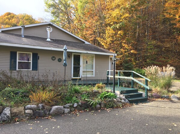 A single-story house with a front porch, a chimney, and a small staircase leading to the front door.