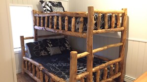 A bunk bed with a wooden frame and patterned bedding. - Cozy and comfortable 1,000 sq. ft. 2-bedroom home with garage. (Bellaire)