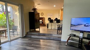 A modern living room with a TV, a dining area, and a kitchen.