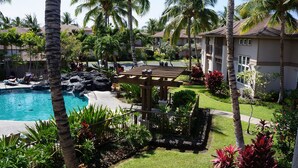 A resort with a swimming pool, palm trees, and a well-maintained garden.
