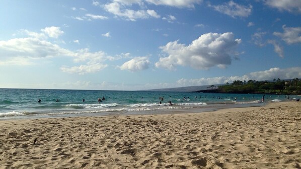 A sandy beach with people swimming and walking along the shore. - 3 Bedroom Spacious Waikoloa Beach Resort (Waikoloa Village)