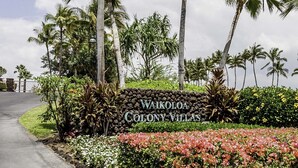 A sign for Waikoloa Colony Villas with a landscaped garden featuring tropical plants and flowers.