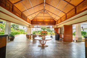 A spacious lobby with a high ceiling, a central round table with a vase of flowers, and a view of the outdoors.