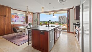 Une cuisine moderne dotée d’un grand îlot central, de meubles en bois et offrant une vue sur l’extérieur.