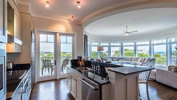 Una cocina moderna con una isla central, ventanas amplias y vista al océano.