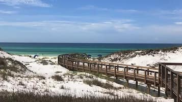 Un paseo marítimo de madera que conduce a una playa con cielos despejados.