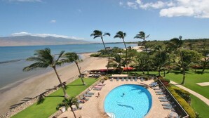 A resort with a swimming pool, beach, and palm trees. - Serene Ocean-Front Condo at Menehune Shores - Unit 520 - Steps from the Ocean! (Kihei)
