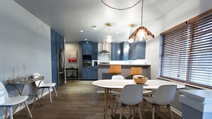 A modern kitchen with blue cabinets, a dining area with a round table and chairs, and a window with blinds. - 3/2
1 Mile to Main St! (Fredericksburg)
