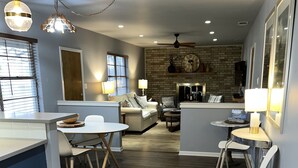 A modern kitchen with a central island, a dining area with a round table, and a living area with a sofa and a coffee table. - 3/2
1 Mile to Main St! (Fredericksburg)