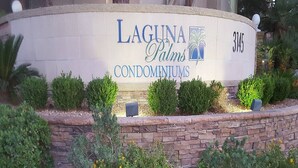 Laguna Palms -nimisen asuinkompleksin kyltti, jonka taustalla on kivimuuri ja hoidettu puutarha.