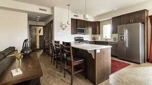 A modern kitchen with dark wood cabinets, stainless steel appliances, and a central island with bar stools.
