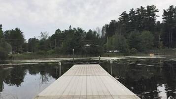 Un muelle de madera que se adentra en aguas tranquilas, con árboles al fondo.