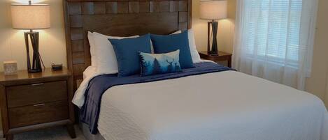 Ein Schlafzimmer mit einem großen Bett, zwei Nachttischen, einer Kopfteil und Wanddekorationen mit Tiermotiven.
