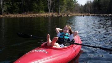 A person in a red kayak on a calm body of water surrounded by trees.
