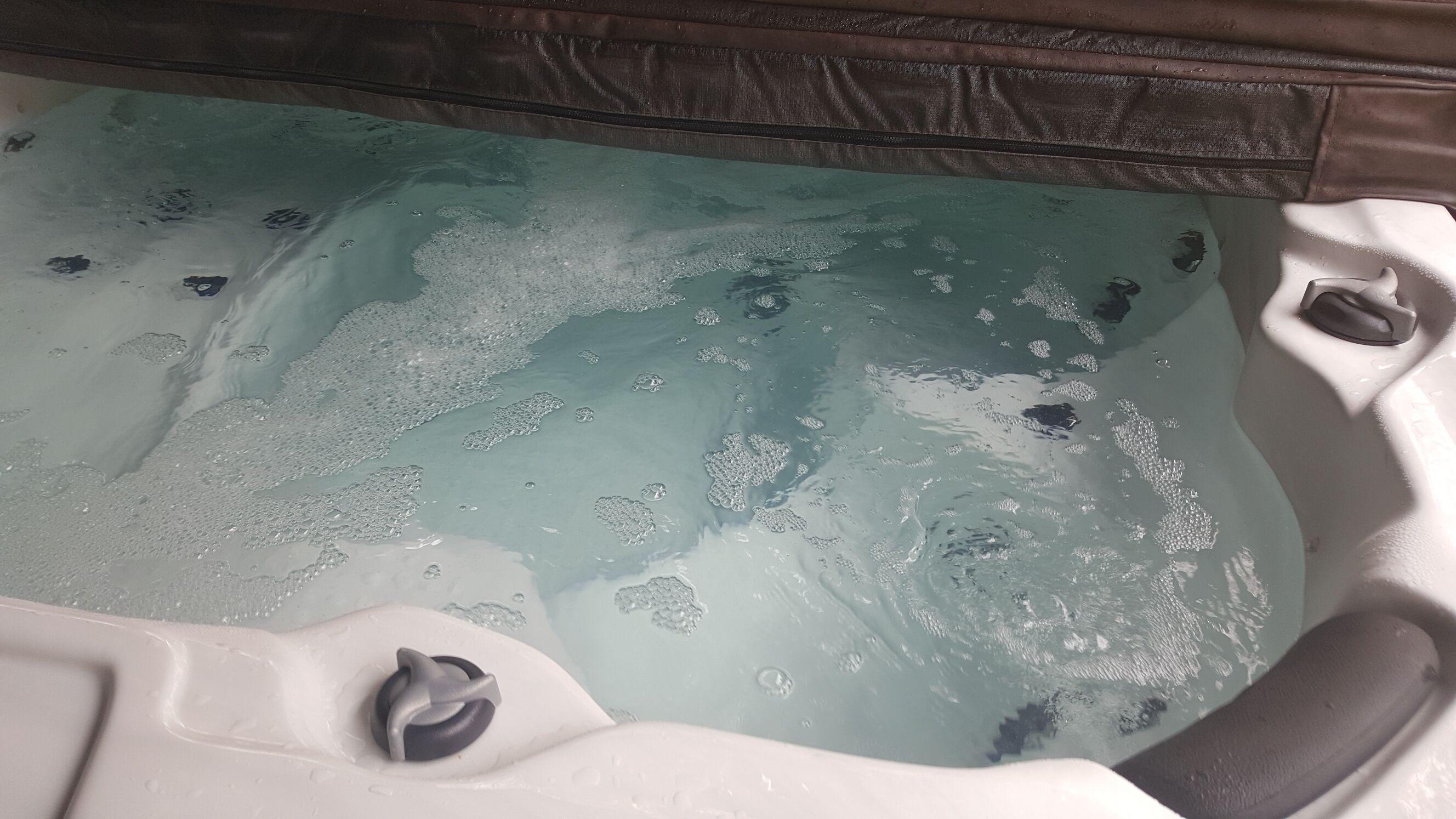 A hot tub with clear water and bubbles, surrounded by white seating areas.