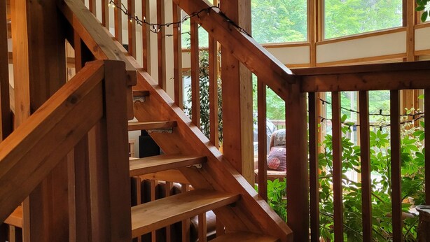 Eine Holztreppe mit Blick auf einen Garten durch große Fenster.