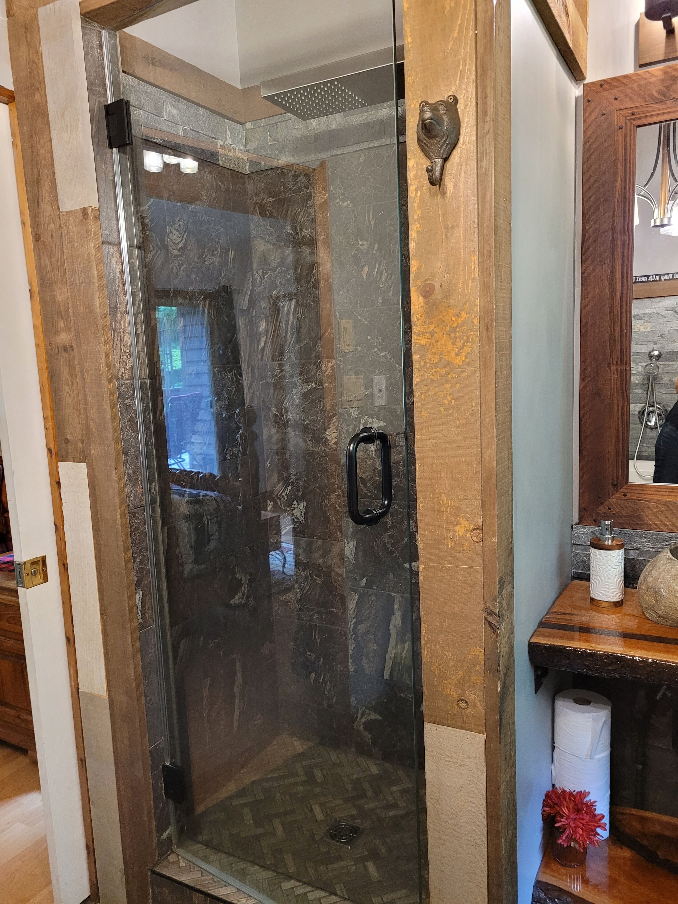 Une douche entièrementClose avec un cadre en bois et un mur en pierre en arrière-plan.