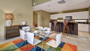 A modern kitchen with white cabinets, a microwave, and a bar area with stools. - Cool Modern Pool & Spa, 2 Bedroom + Private Den House. (Palm Springs)