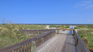 Un muelle de madera que conduce a una playa con vista despejada al océano.