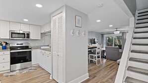 Una cocina moderna con armarios blancos, electrodomésticos de acero inoxidable y piso de madera.