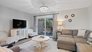 Una sala de estar con televisor, sofá y comedor con mesa y sillas.