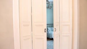 Quarto com cama, lustre e porta branca.