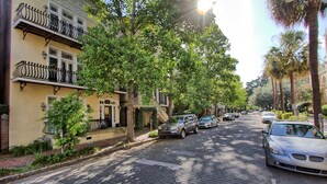 Une rue pavée bordée d’arbres et de voitures garées.
