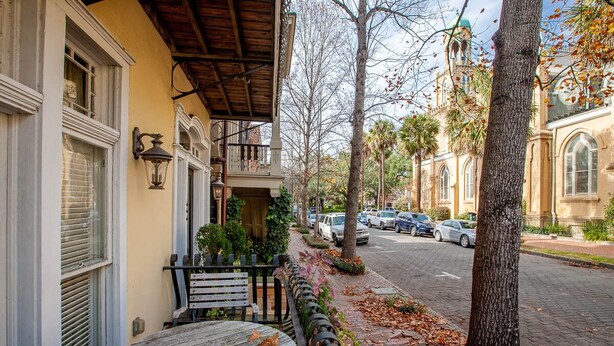 Une vue de rue avec un immeuble doté d’un balcon, d’une table et d’un banc.