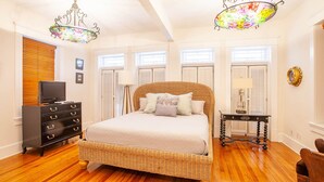 Une chambre à coucher avec un lit en osier, une commode en bois et un lustre.