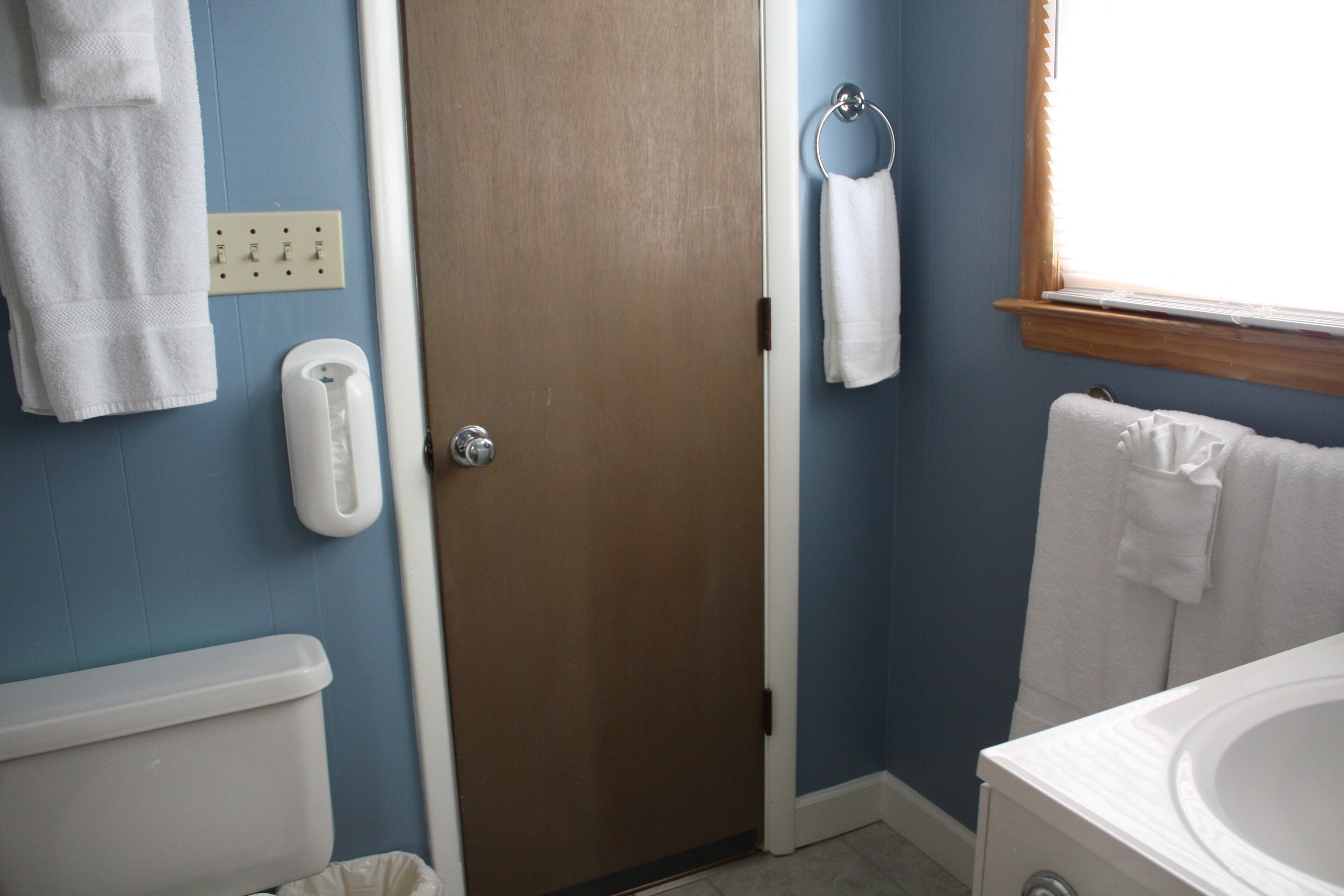 A bathroom with a toilet, a sink, a towel rack, and a door.