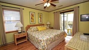 A bedroom with a bed, nightstand, lamp, ceiling fan, and large windows. -  @ Ocean Front Guest Friendly Home "An Emerald On The Beach" (Sunset Beach)