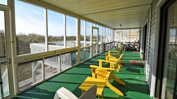 A covered outdoor area with yellow chairs and a green floor, overlooking a scenic landscape. -  @ Ocean Front Guest Friendly Home "An Emerald On The Beach" (Sunset Beach)