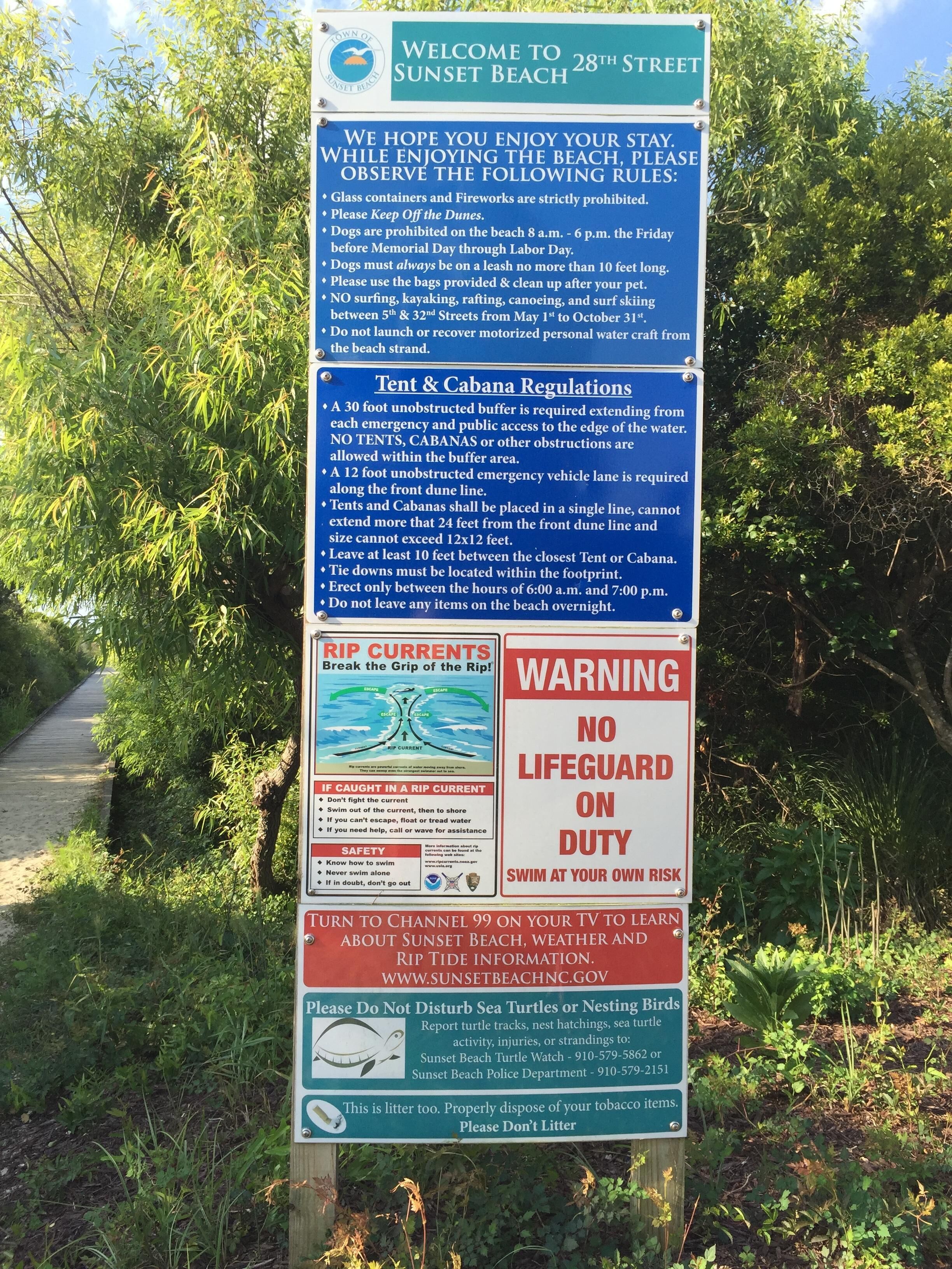 A sign with beach rules and regulations, including no glass containers, fireworks, and dogs on the beach at certain times.