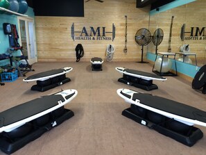 A fitness center with exercise equipment, including treadmills and weights, and a wooden wall with the logo "AMI Health & Fitness".