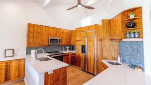 A modern kitchen with wooden cabinetry, stainless steel appliances, and a central island.