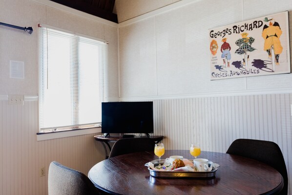 A room with a round table, a television, and a poster on the wall.