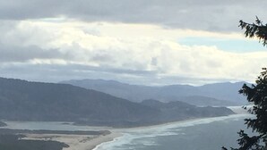 Un paysage côtier avec une plage, des vagues et des montagnes à l’horizon.