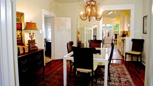 A dining area with a chandelier, a table, and chairs. There is a mirror on the wall and a lamp on a side table. - Refuge in the heart of Montrose (Houston)