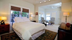 A spacious bedroom with a large bed, a sitting area with a chair, and a view of the outdoors. - Refuge in the heart of Montrose (Houston)
