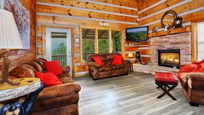 Un acogedor interior de cabaña de madera con dos sofás de cuero, una chimenea y un televisor.