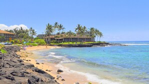 A beach resort with a rocky shoreline, palm trees, and a clear blue sky. - Prince Kuhio Poipu ~ Ocean View, quiet, comfortable, end unit-ground floor (Koloa)