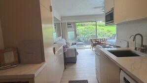 A modern kitchen with a central island, a dining area with a view, and a built-in microwave. - Prince Kuhio Poipu ~ Ocean View, quiet, comfortable, end unit-ground floor (Koloa)