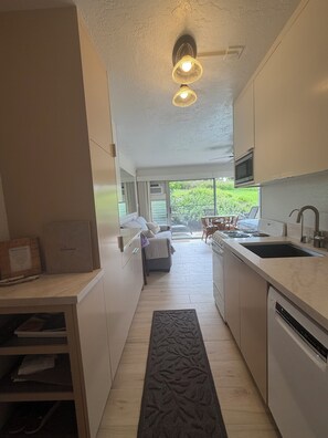 A modern kitchen with a central island, a dining area with a view, and a built-in microwave. - Prince Kuhio Poipu ~ Ocean View, quiet, comfortable, end unit-ground floor (Koloa)