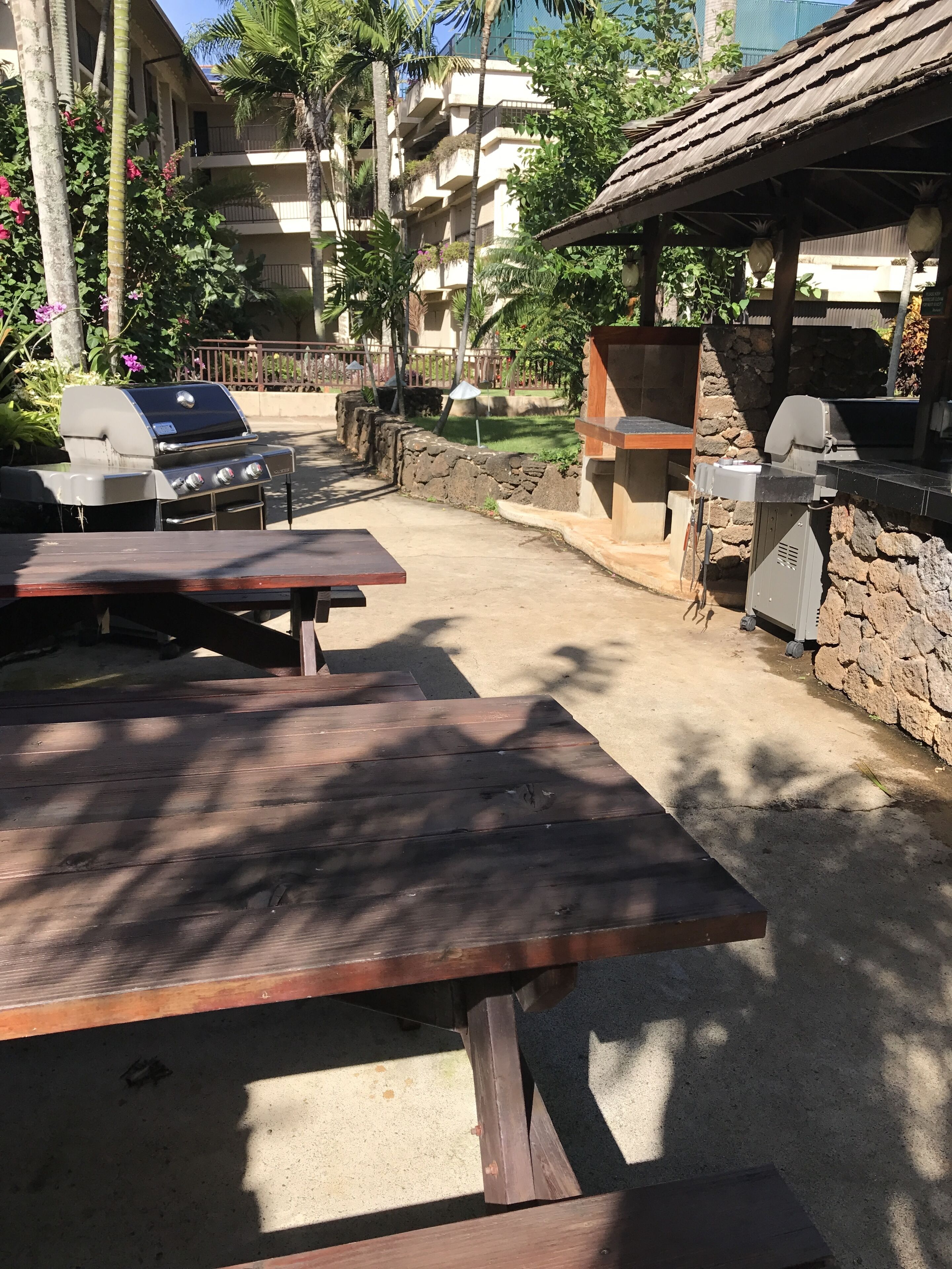 An outdoor patio with a barbecue grill, seating area, and stone walls.